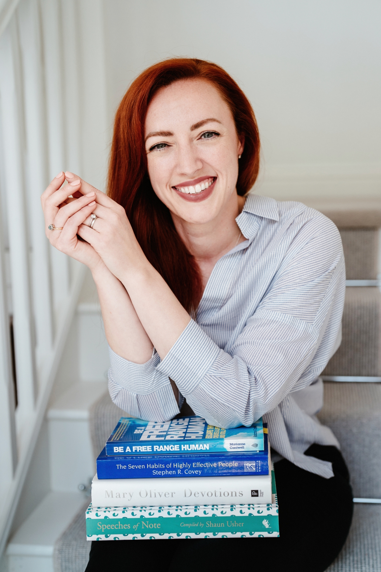 Dr. Amy-Jo displays a confident and intellectual demeanor in a portrait, grasping significant books related to her field of expertise.