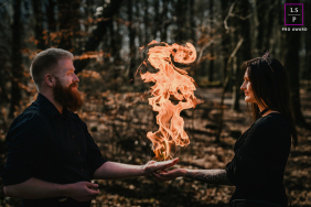 In the forests of Münsterland, this couple balances a towering flame between their hands like a living symbol of devotion. The dark woodland backdrop and dramatic firelight create a photograph filled with mystery, intensity, and theatrical romance.