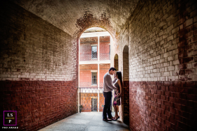 Framed by the long brick corridor in San Francisco, the couple leans into a quiet kiss that feels hidden from the outside world. The arching ceiling and dramatic perspective pull the eye inward, turning intimacy into the undeniable center of attention.