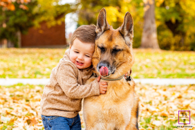 In Reno, Nevada, a young boy hugs his German Shepherd tightly as autumn leaves blanket the ground around them. The dog’s perfectly timed expression adds humor and charm, turning this warm outdoor portrait into a sweet celebration of friendship and trust.