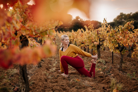 A lifestyle photographer took a picture of a yoga teacher at M Yoga & Massage Montélimar, Drome, France in a grape vineyard wearing clothes that matched the colors of the leaves.