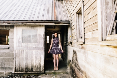 Seattle WA teen lifestyle portrait of a girl holding out her dress in a rural farm building