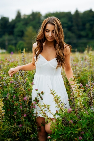 Vertical picture of Seattle girl walking through tall grass for a teen portrait in Washington