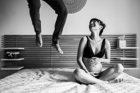 Sessão de imagens de maternidade interna do estilo de vida de Perpignan durante casal no quarto, pai pulando na cama