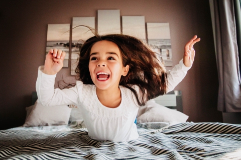 Imagem do retrato de estilo de vida criativo da França da menina que pula na cama em casa