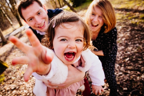 Auvergne-Rhone-Alpes Lifestyle Family Photographer created this artistic portrait of A family having fun while The little girl tries to save herself from her parents