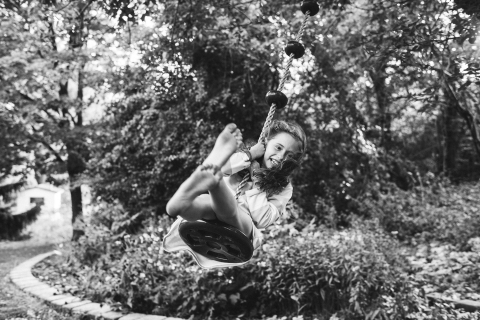 Toronto young girl poses for a Lifestyle Portrait Session while swinging on a tree, her barefeet dirty from running around her backyard