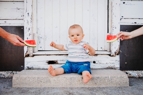 France toddler poses for a Lifestyle Portrait Session as the boy is little boy has a choice for his share of watermelon. Mom and Dad want to know which of the two he will choose