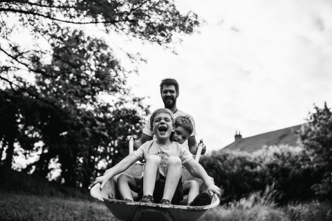 Família Doubs posando para um retrato do estilo de vida durante um passeio de carrinho de mão com o papai em BW