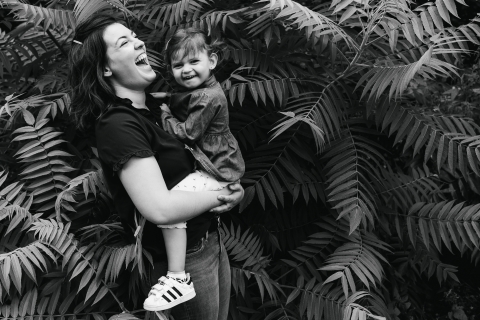 This is a lifestyle photo from Doubs of a young child in the ferns with mom in BW