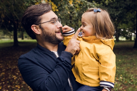 Dad and daughter enjoy a sunny day in Bourg-en-Bresse, France, touching each others noses in the park surrounded by trees