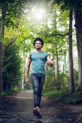 A man in Atlanta, GA takes his daily walk on a paved trail surrounded by trees in a peaceful forest setting