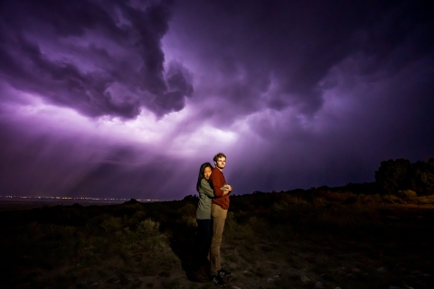 Um casal faz uma pose perto de uma tempestade em Great Sand Dunes, Colorado, sob um céu nublado roxo