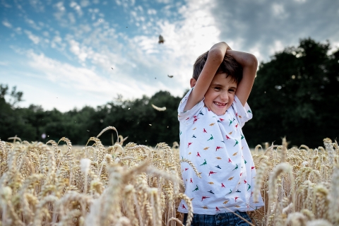 A boy finds delight in the golden field of grain of Dijon, France, adding a touch of joy to this picturesque lifestyle portrait.