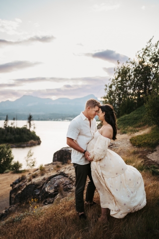 Aguardando ansiosamente seu filho, os novos pais farão uma pose nas falésias pitorescas perto da água em Cascade Locks, Oregon, para um retrato do estilo de vida
