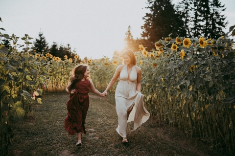 This captivating lifestyle portrait, shot in Washington state, features a heartwarming stroll for a mother and daughter exploring a stunning field of sunflowers