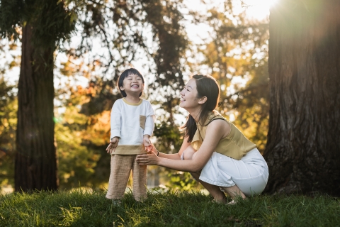 This captivating lifestyle portrait captures a heartwarming encounter between a mother and son, set amidst the towering trees and lush grass in Mountain View, California