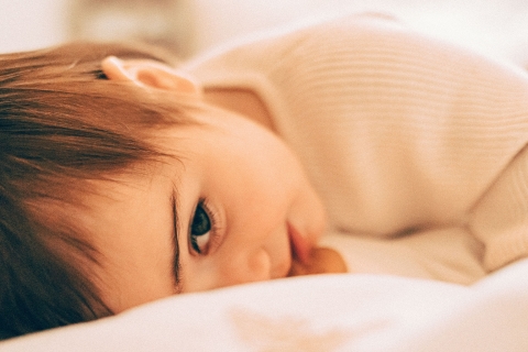 This lifestyle portrait captures a shy baby in Seattle, Washington, sneakily peering at a mysterious guest. An adorable face full of wonder.