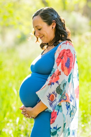 This stunning lifestyle portrait captures the essence of maternity as a woman lovingly holds her belly amidst a backdrop of lush greenery in Reno, NV