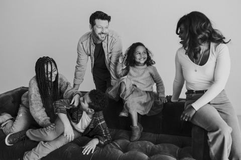 This is a black and white photo taken in Austin, Texas, showing a family relaxing on their couch at home, enjoying some quality time together.