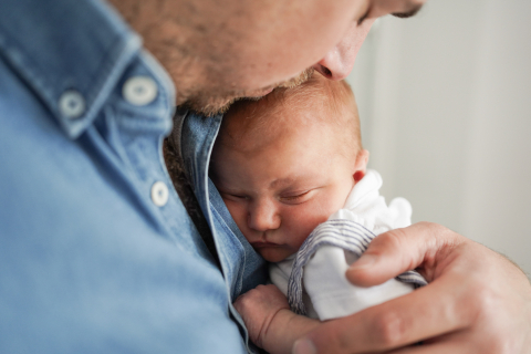 Em Paris, França, um pai gentil mantém suavemente o seu bebé perto do coração durante uma sessão fotográfica que captura os laços especiais da sua família.