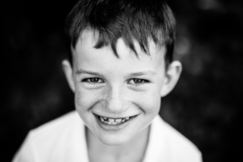 Uma fotografia alegre de um menino em um ambiente sereno na França, sorrindo para a câmera.