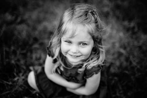 Cenário rural francês para um retrato deslumbrante em preto e branco de uma menina feliz olhando para a lente com um sorriso doce.
