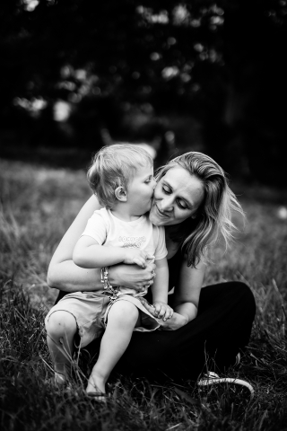 Amor compartilhado nos campos de Val d'oingt, um beijo precioso entre uma mãe e seu filho, capturado em preto e branco atemporal.