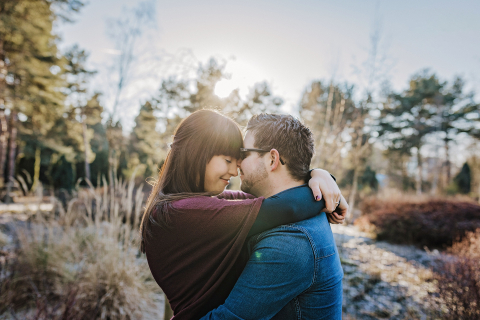 Um retrato romântico na natureza, banhando-se na luz quente do sol de inverno. Um casal abraçado, nariz com nariz, emoldurado pelas árvores em Dortmund, Alemanha.