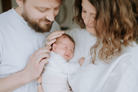 Um retrato de família em Haut de France, mostrando os pais e seu bebê, todos vestidos de branco.