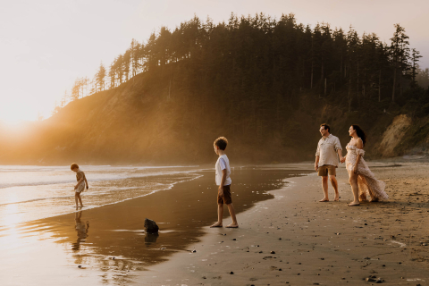 Uma família feliz brinca nas praias arenosas de Cannon Beach, Oregon, com crianças brincando alegremente nas ondas suaves