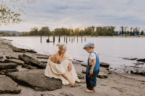 Em Portland, Oregon, uma mãe e seu filho agacham-se juntos, observando atentamente a areia, enquanto compartilham um momento tranquilo de exploração e descoberta.
