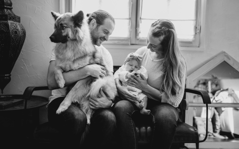 Uma família do Loire se senta confortavelmente em um banco da sala de estar. Um dos pais segura um cachorro, o outro embala um bebê.
