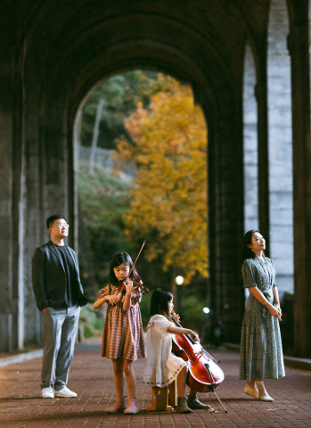 Dois jovens músicos tocam instrumentos clássicos em frente aos grandes arcos do The Met Cloisters, adicionando um toque de charme do Velho Mundo ao seu retrato de outono em Nova York."