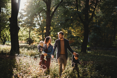 Uma família de quatro pessoas caminhando por uma floresta ensolarada em Boston, Massachusetts.