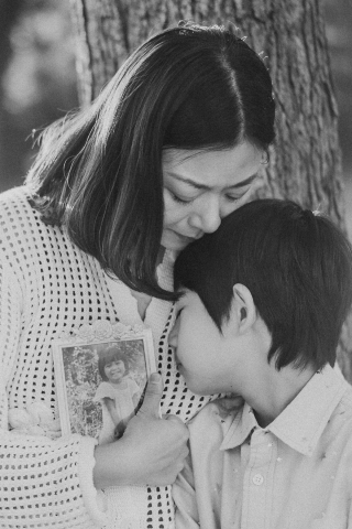 Retrato de mãe e filho amorosos em um parque de Boston, capturando o calor entre eles enquanto seguram uma foto de um membro da família desaparecido.