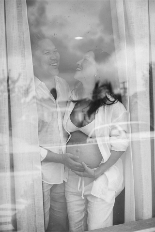 Um casal feliz no sul da Califórnia, especificamente em Los Angeles, olhando alegremente um para o outro com antecipação enquanto se preparam para receber seu primeiro bebê. Eles são retratados no conforto de sua casa acolhedora e aconchegante, abraçando a excitação.