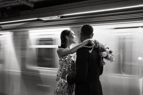No Brooklyn, Nova York, uma sessão de fotos em preto e branco captura um casal no metrô, com o movimento do trem passando. A foto dinâmica destaca a conexão deles em meio ao cenário urbano agitado.