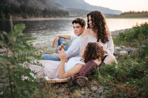 Em Washington, EUA, uma mãe e seus filhos adolescentes sentam-se à beira do rio, aproveitando um tempo de qualidade juntos.