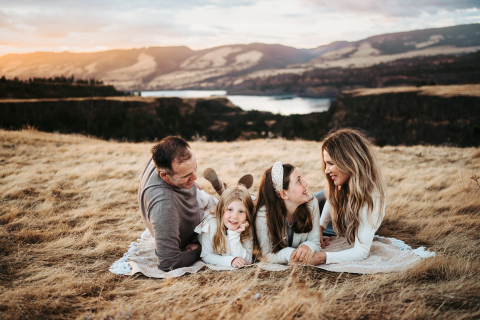 Em Washington, EUA, uma linda família relaxa em um cobertor em um campo de grama seca no desfiladeiro, aproveitando o tempo juntos.