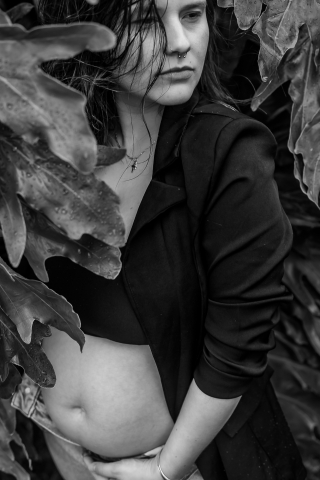 Em Vitorino, PR, um retrato em preto e branco captura uma futura mãe cercada por folhas de inverno. A cena enfatiza sua elegância serena e a beleza serena deste período especial.