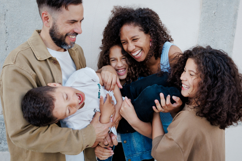 Em Paris, França, uma família aproveita o tempo junta, rindo e brincando. Eles são retratados em um retrato alegre, com todos engajados e sorridentes.