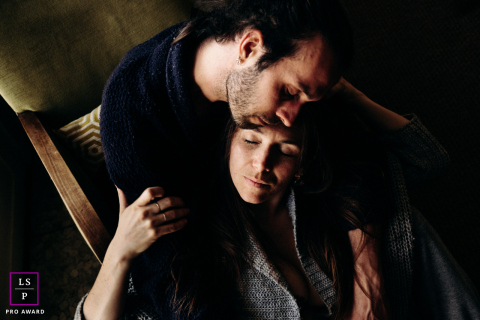 Sua conexão amorosa: um retrato íntimo em Les Gites du Berry Em Les Gites du Berry, em Indre, ele senta-se confortavelmente em uma cadeira enquanto ela se senta no chão, entre suas pernas. A proximidade gentil e as expressões ternas realçam uma conexão tranquila e amorosa.