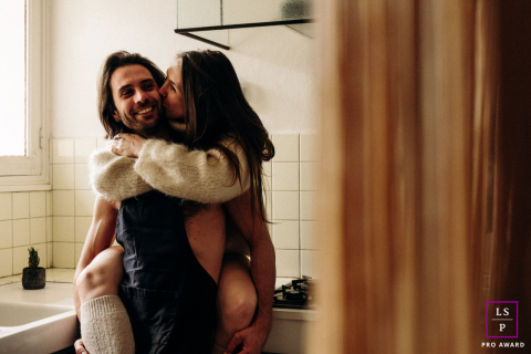 No coração da França, o romance na cozinha floresce Na cozinha do Les Gites du Berry, em Indre, ela se senta alegremente no balcão, envolvendo-o com as pernas por trás. A interação afetuosa entre eles transmite uma sensação de intimidade e cumplicidade alegre.