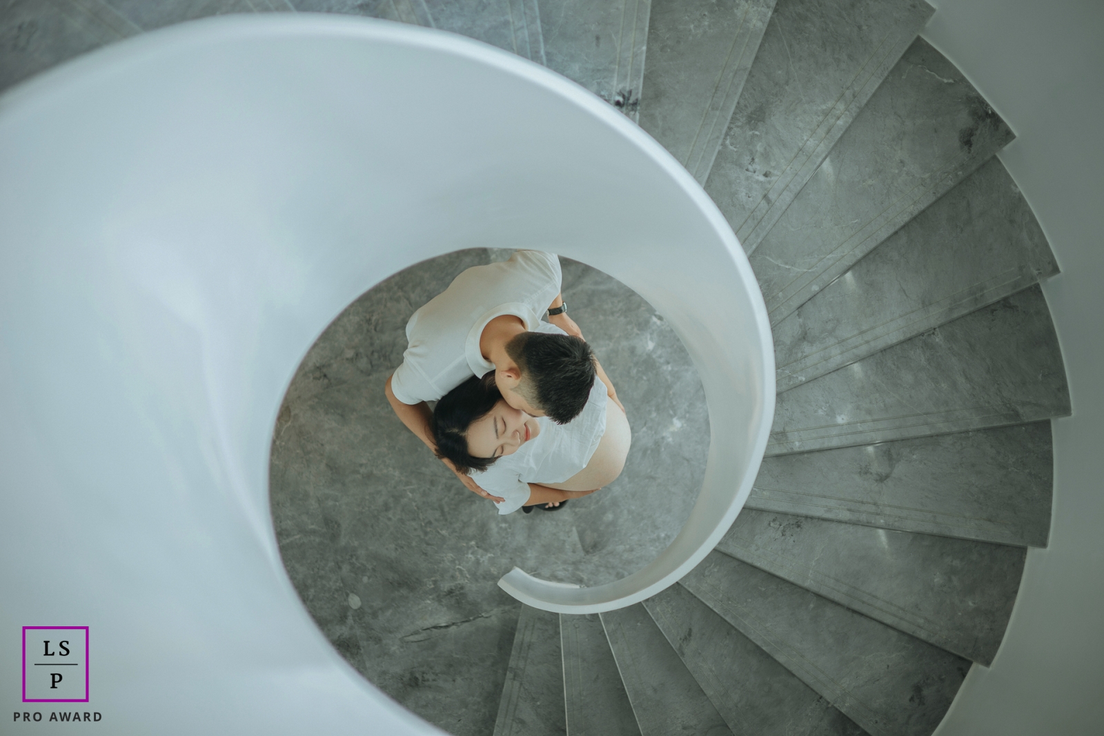 This lifestyle photo session took place in Hangzhou, China and featured a pregnant mother and father posed below and center of a spiral staircase