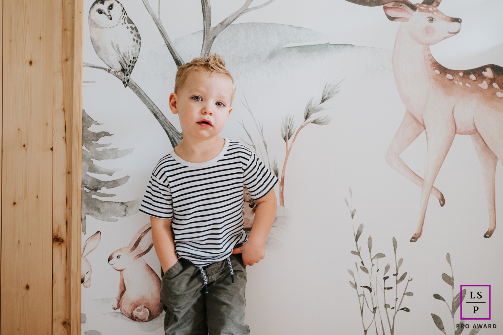 Na Alsácia, um jovem rapaz posa confiantemente para a câmera, exibindo seu charme brincalhão, em um cenário pitoresco