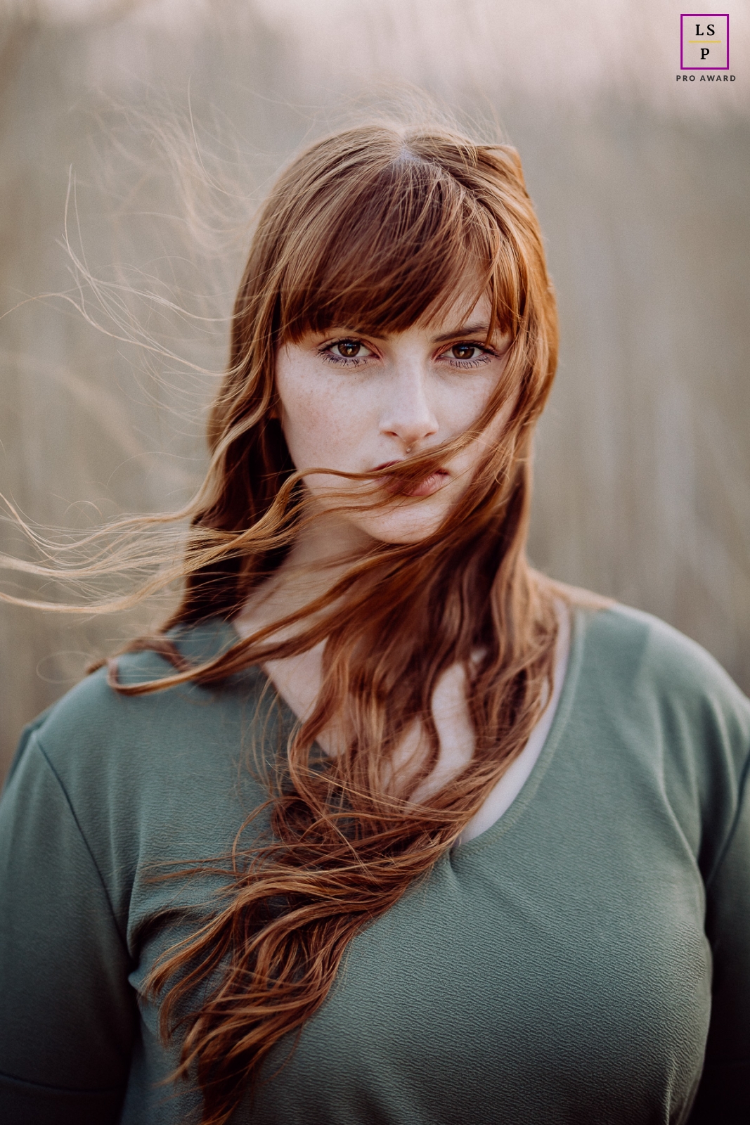 A young woman with long, red hair stands outdoors in Mainz, Germany as the wind blows her hair
