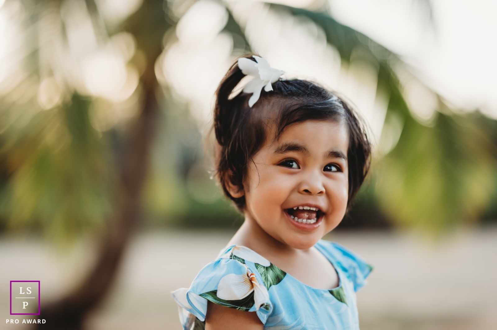 This cheerful toddler's contagious laughter and joy illuminate a stunning Oahu sunrise, with beautiful bokeh palm trees adding to the picturesque scene in the United States