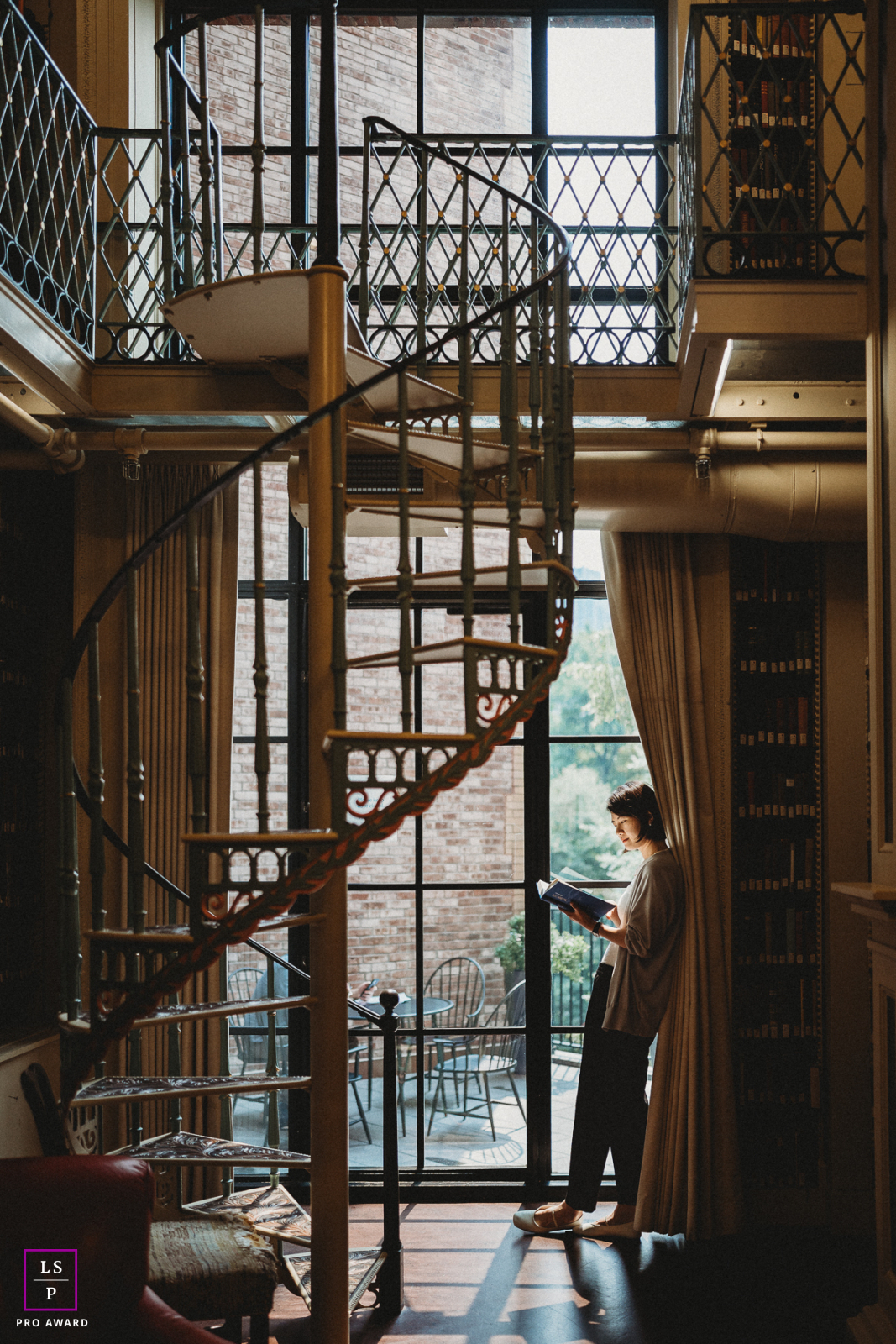 Uma mulher parada perto de uma escada em espiral em uma biblioteca, aproveitando um momento de tranquilidade na cidade de Boston.