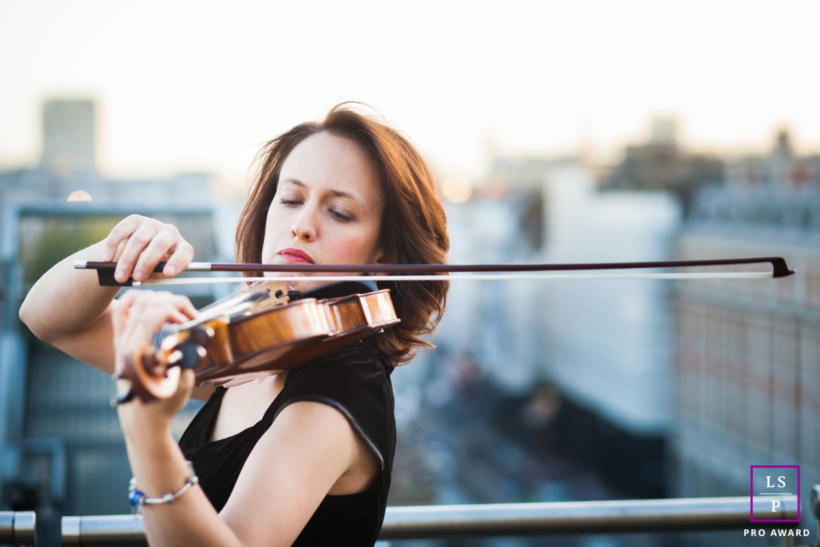 Uma sessão de fotografia de estilo de vida de marca de negócios foi realizada em um telhado em Londres, Inglaterra, apresentando uma mulher tocando violino com a cidade fora de foco ao fundo